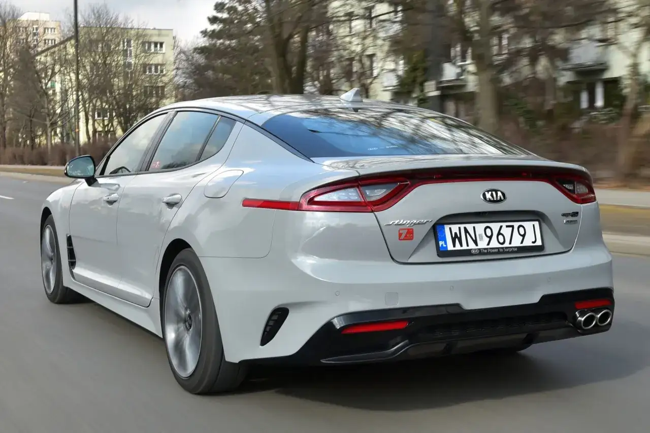 Jasnoszary Kia Stinger GT z polskimi tablicami rejestracyjnymi WN 9679J jedzie po miejskiej drodze.