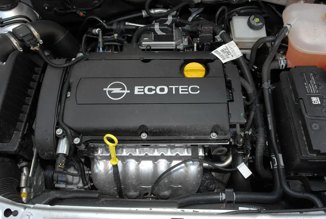 Silnik Ecotec w Oplu Astra H 1.6 benzyna. Widoczny jest czarny kolektor, żółta miarka oleju i akumulator GM.