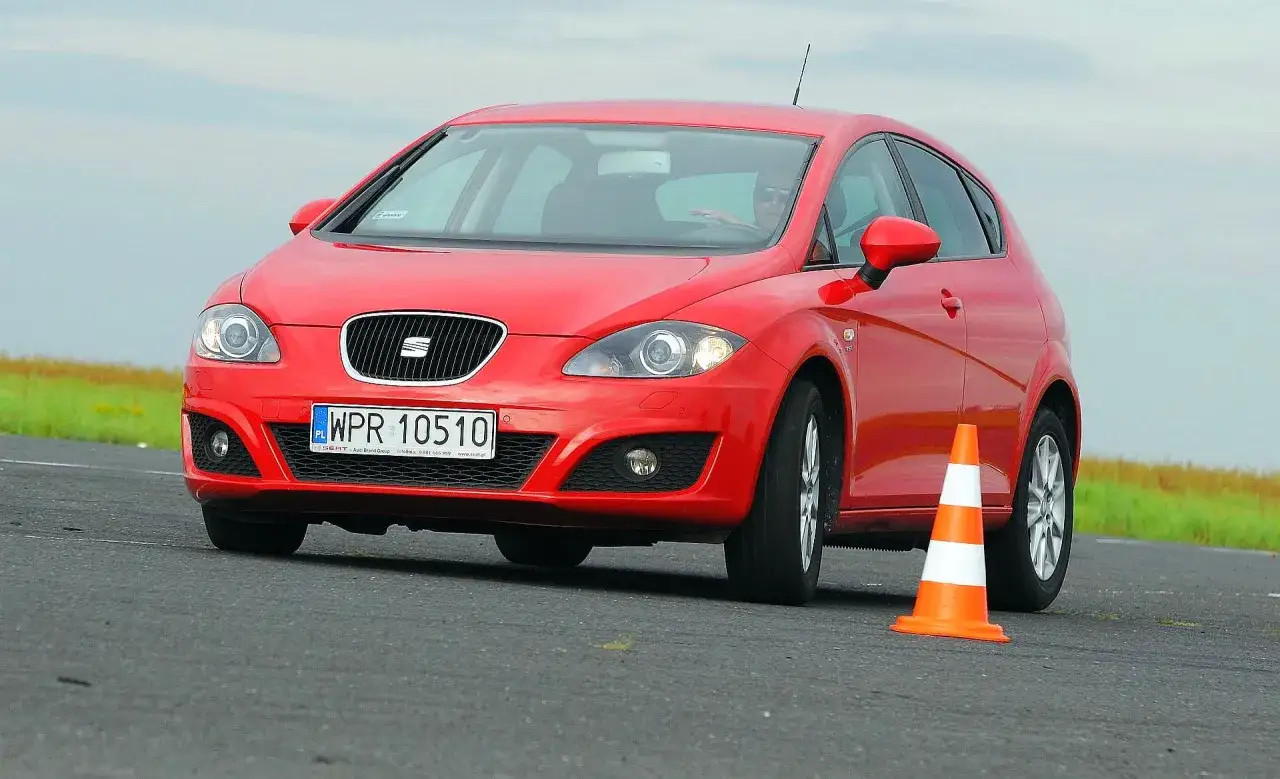 Czerwony Seat Leon 2 manewruje między pachołkami na torze.