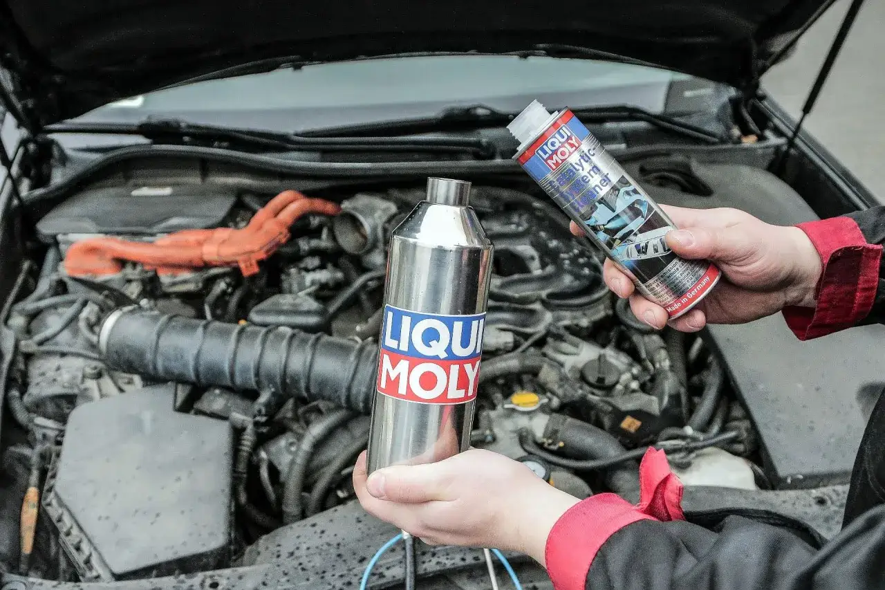Osoba trzyma puszkę i butelkę z płynem do czyszczenia katalizatora Liqui Moly.