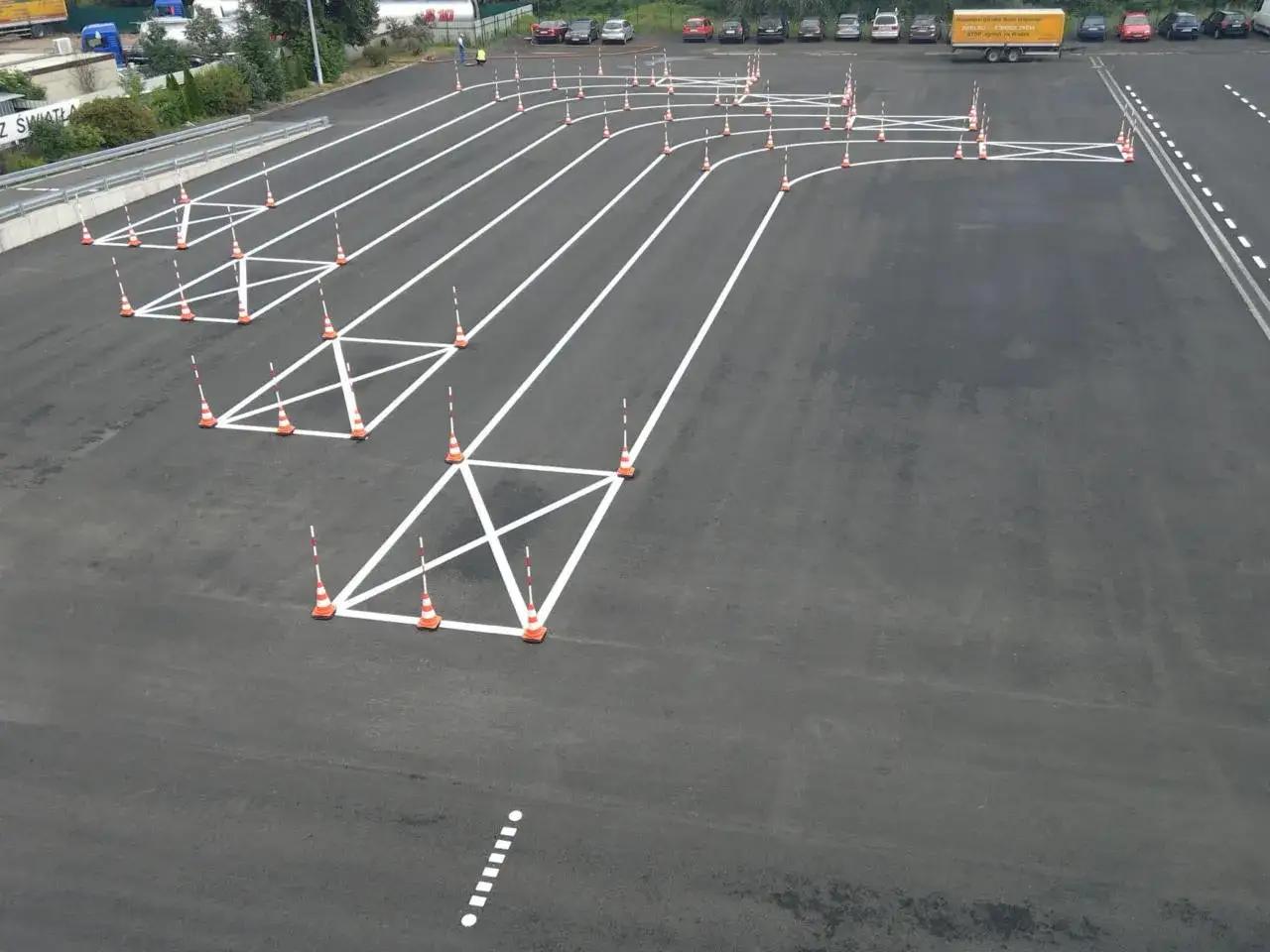 Plac manewrowy z pachołkami i białymi liniami wyznaczającymi tor jazdy. Zastanawiasz się, ile trwa egzamin na prawo jazdy?
