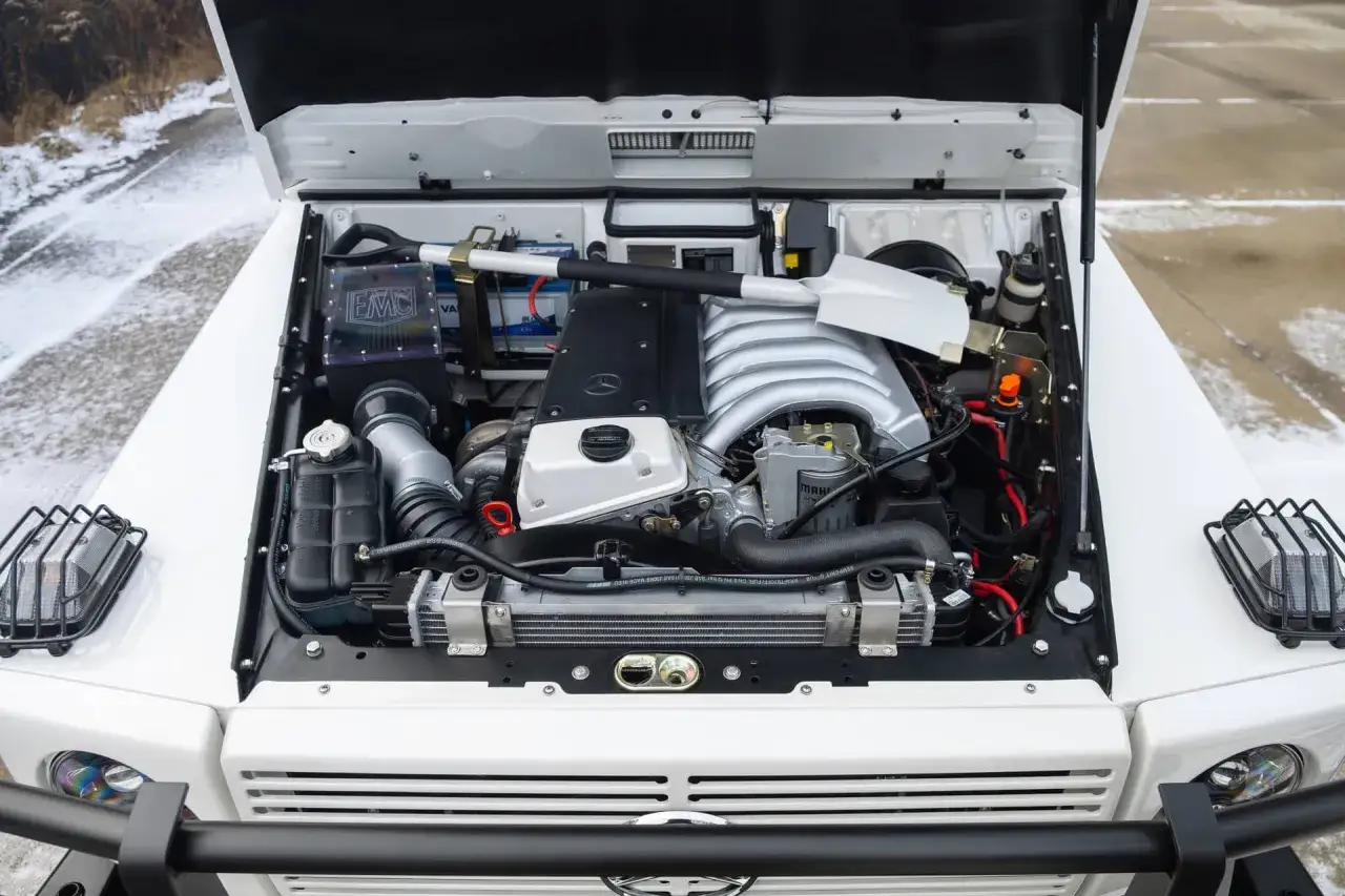 Silnik V8 OM606 w białym Mercedesie G-klasa, gotowy do jazdy w zimowych warunkach.