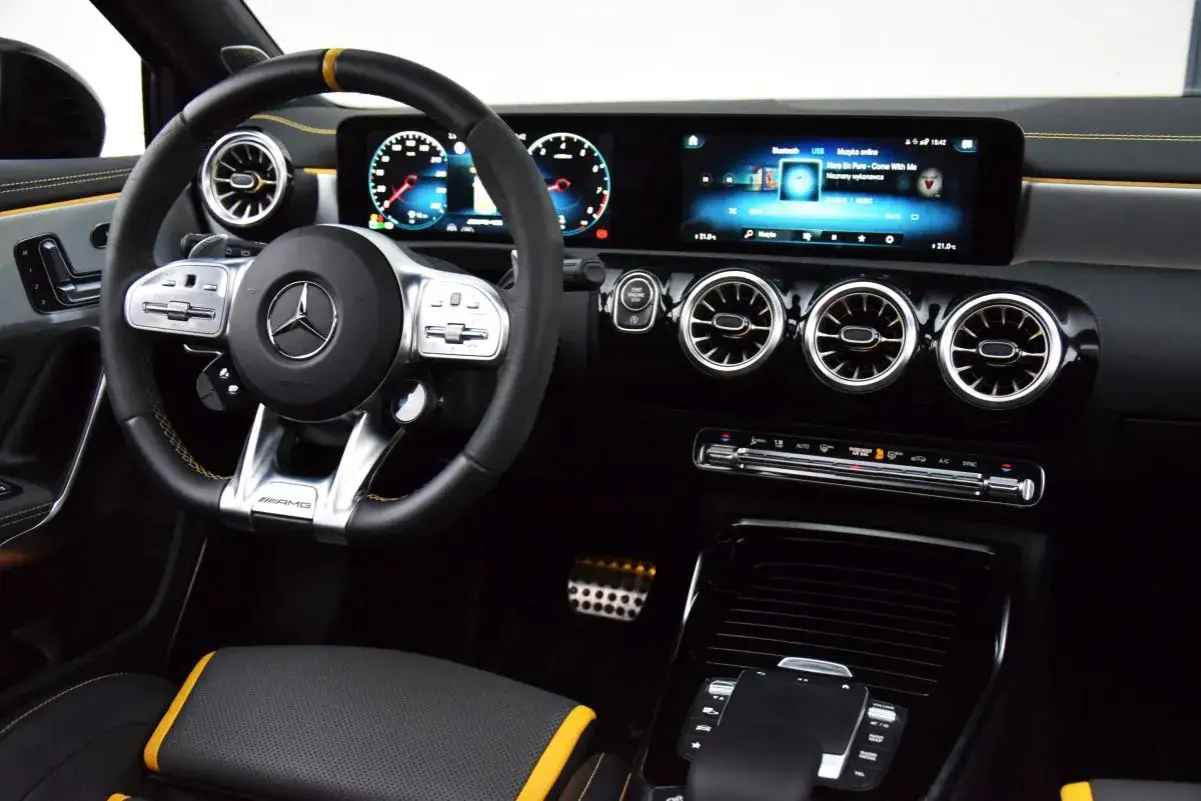Wnętrze sportowego A45 AMG z ekranem multimediów, cyfrowymi zegarami i żółtymi akcentami.