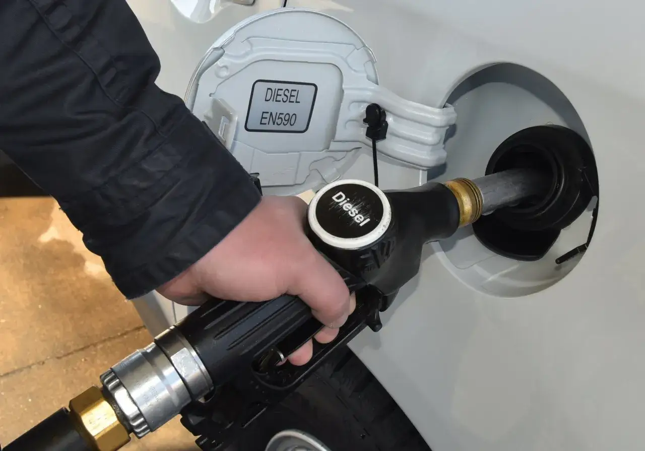 Ręka trzymająca pistolet paliwowy z napisem 